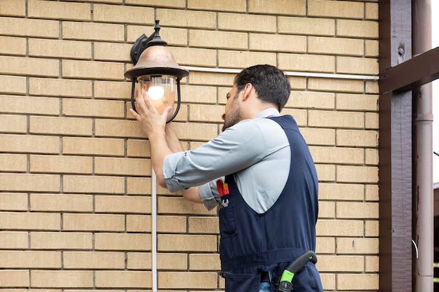 Electrician mounting an outdoor lantern light on a brick wall